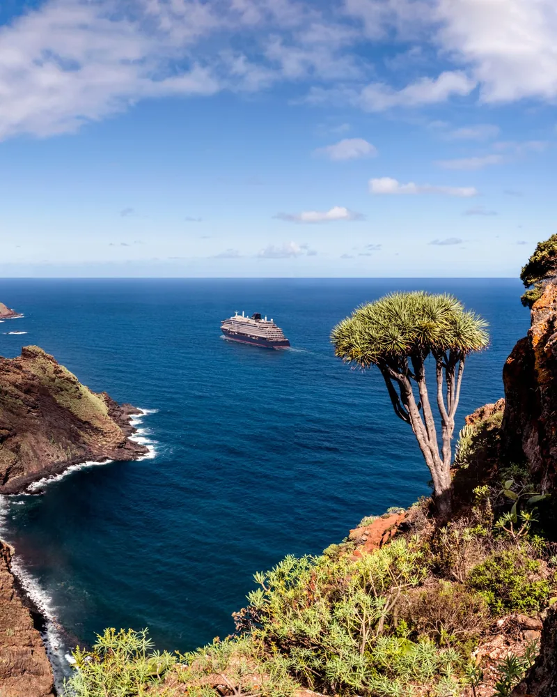 A volcanic Atlantic island coastline, dark cliffs dropping into clear water