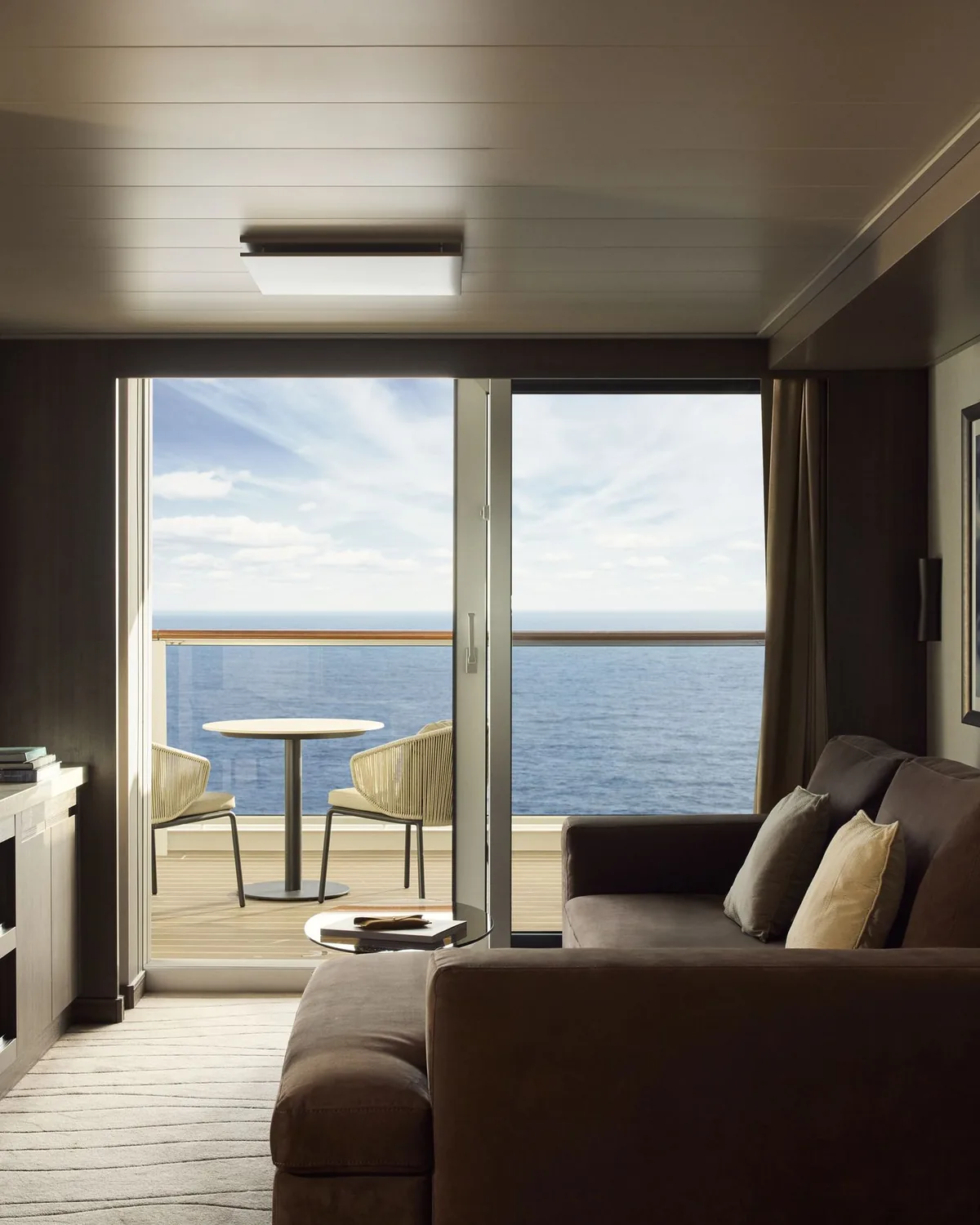 The living room of an Ocean Residence, a long sofa facing floor to ceiling glass and the terrace beyond