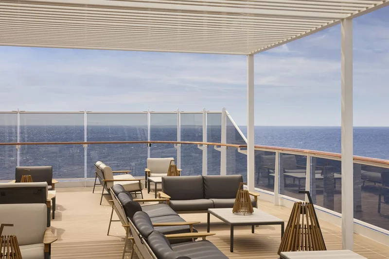 The Sky Lounge at dusk, low seating arranged along a wall of windows over the bow