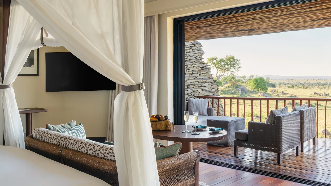 A Savannah Room four poster bed with the doors open to a covered deck over the Serengeti plains