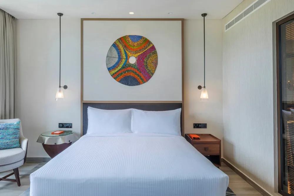 The king bed in a Deluxe Room at Gran Meli&aacute; Arusha, under a colorful beaded artwork