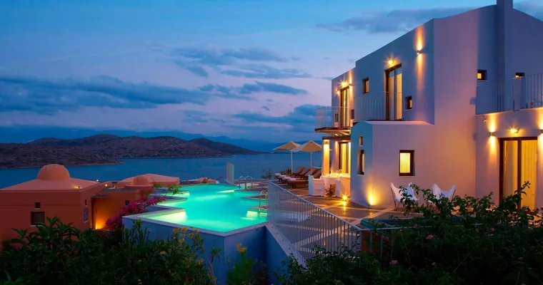 A lit private pool and white villa at Domes of Elounda in the evening