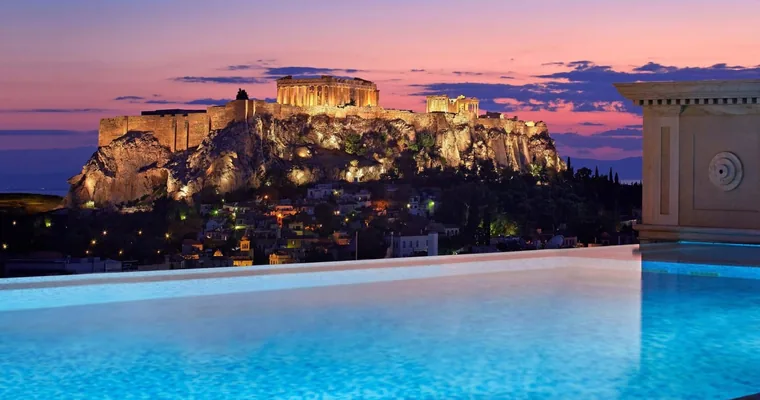The rooftop pool at Hotel Grande Bretagne with the floodlit Acropolis behind it at dusk