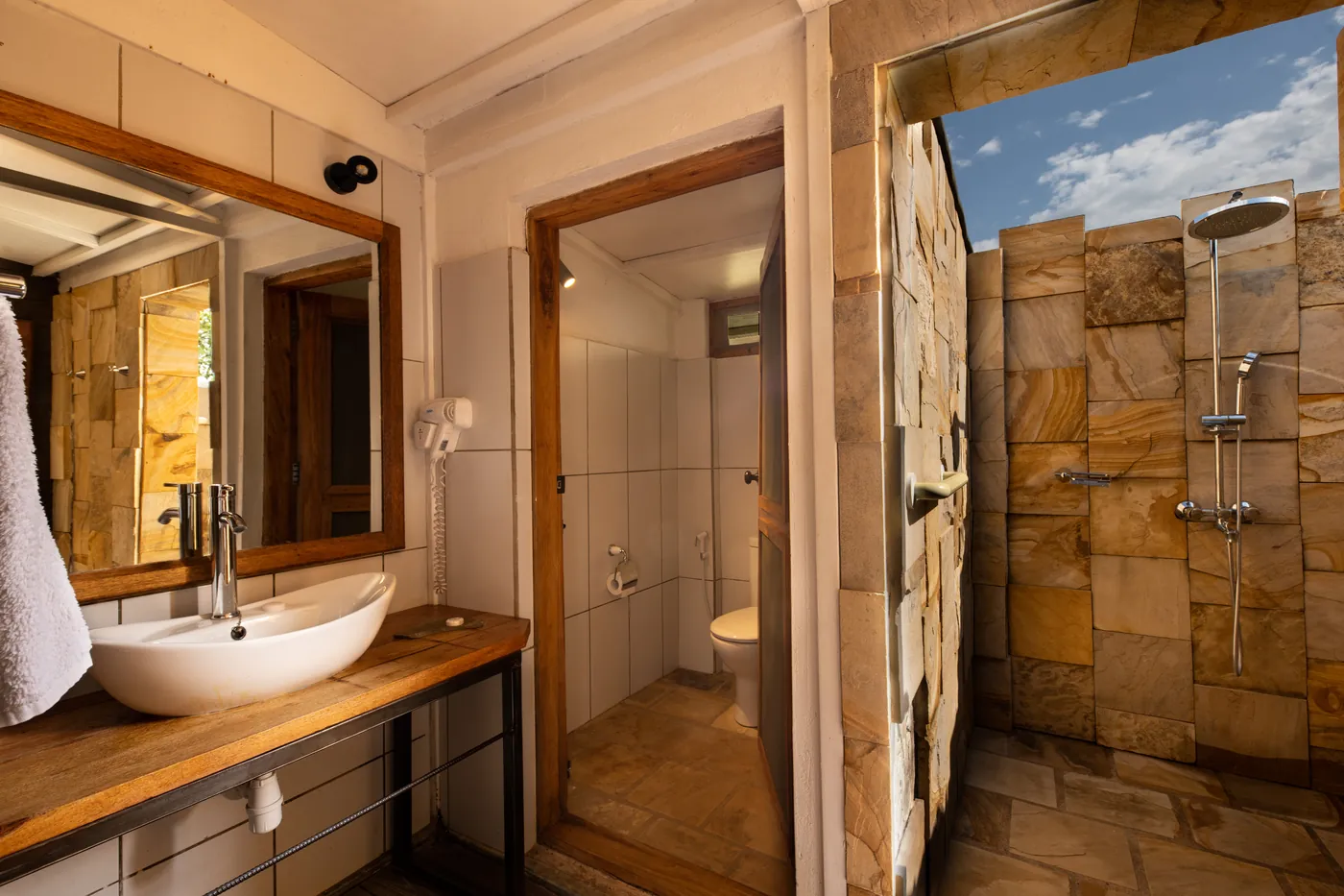 The tent bathroom with a stone walled outdoor rain shower open to the sky
