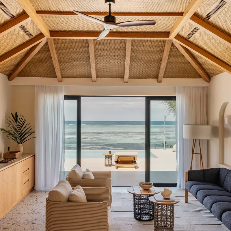 The villa living room with sliding doors open to the pool terrace and the ocean